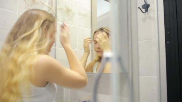 Güzel genç kadın aynanın önünde makyaj yapıyor. — Stok video