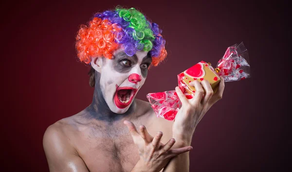 Scary clown with spooky makeup and more candy — Stock Photo, Image