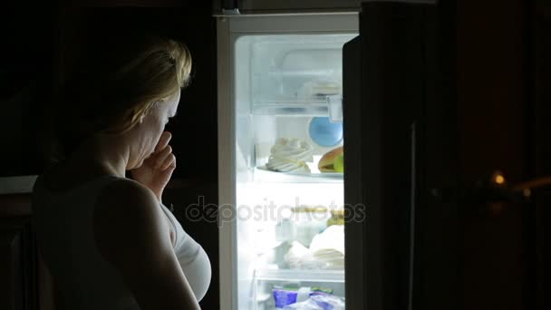 La mujer abre el refrigerador por la noche. bulimia, sándwich, pastelería — Vídeo de stock