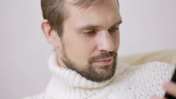 Jeune homme barbu dans une veste sur le canapé avec une tablette — Video