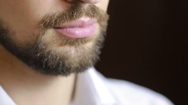 O homem sorri. Um homem com uma barba a sorrir. Close-up. lábios sexy — Vídeo de Stock