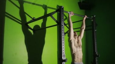 Gömleksiz adam yatay bir çubuk üzerinde Mide Egzersizleri yapıyor. CrossFit. egzersiz