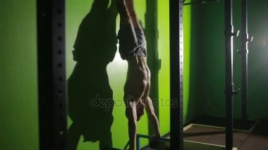 Baş aşağı duran süre ellerinin üstünde şınav çıplak gövde ile sporcu