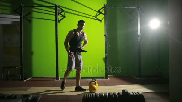 Młody człowiek sportowe robi kettlebell swing poćwiczyć w siłowni. CrossFit — Wideo stockowe