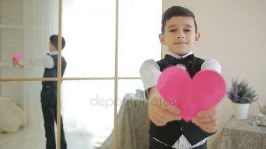 Çok mutlu bir gülümseyen çocuk kırmızı bir kalp gösteriyor. Sevgililer günü,