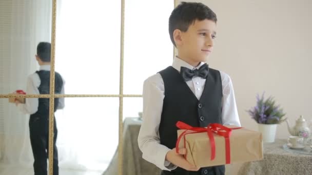 Gadstuke alegre chico en pajarita celebración de un regalo con — Vídeos de Stock