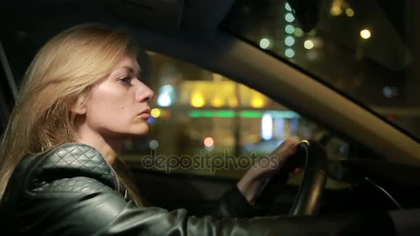 Loira jovem mulher dirigindo um carro à noite — Vídeo de Stock