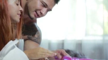 Close up of a sexy couple kissing and playing in bed. sex toys. lot of dildo