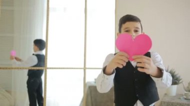 Çok mutlu bir gülümseyen çocuk kırmızı bir kalp gösteriyor. Sevgililer günü,