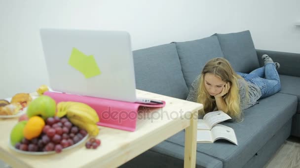Joven estudiante haciendo la tarea en casa en el sofá — Vídeo de stock