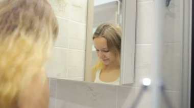 Güzel genç kadın aynanın önünde makyaj yapıyor.