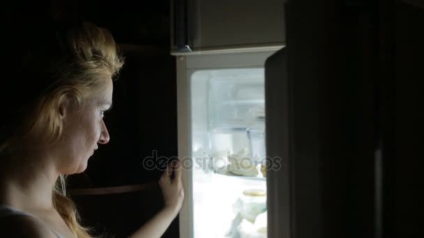Женщина открывает холодильник по ночам. булимия, сэндвич, кондитерская — стоковое видео
