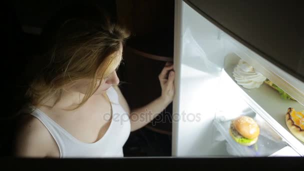 La mujer abre el refrigerador por la noche. bulimia, sándwich, pastelería — Vídeo de stock