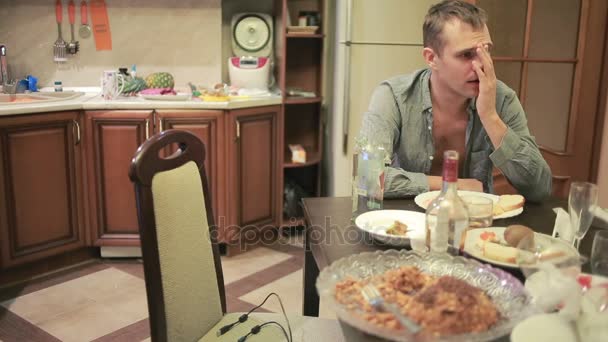 Fiatal férfi a másnaposság, az asztalnál, a konyhában. buli után — Stock videók