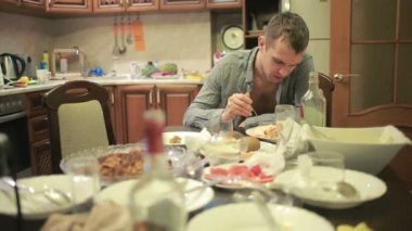 Akşamdan mutfak masasında olan genç adam. partiden sonra