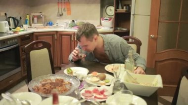 Akşamdan mutfak masasında olan genç adam. partiden sonra