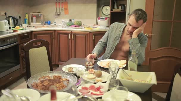 Jeune homme avec une gueule de bois à la table dans la cuisine. après la fête — Video