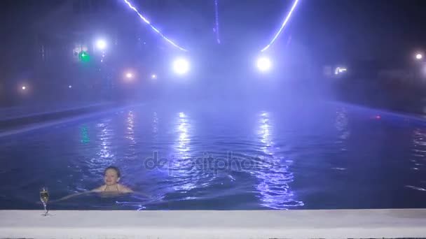 Mulher à noite na piscina com água termal com uma taça de champanhe — Vídeo de Stock