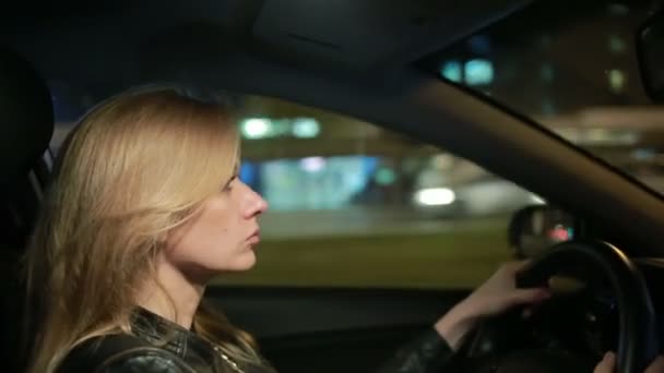 Bionda giovane donna alla guida di una macchina di notte — Video Stock