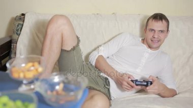 Bir karanlık odada joystick video oyunları oynarken bir kanepede oturan adam