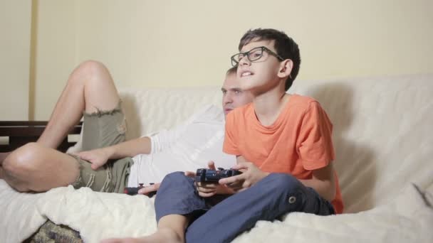 Far och son spela spel inne i deras hus på soffan — Stockvideo