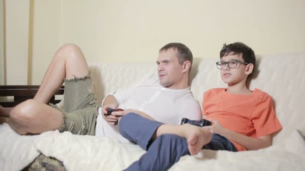 Vater und Sohn spielen Videospiel in ihrem Haus auf der Couch — Stockvideo