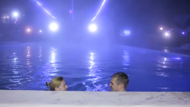 Pareja hombre y mujer nadando en una piscina con agua termal por la noche . — Vídeos de Stock