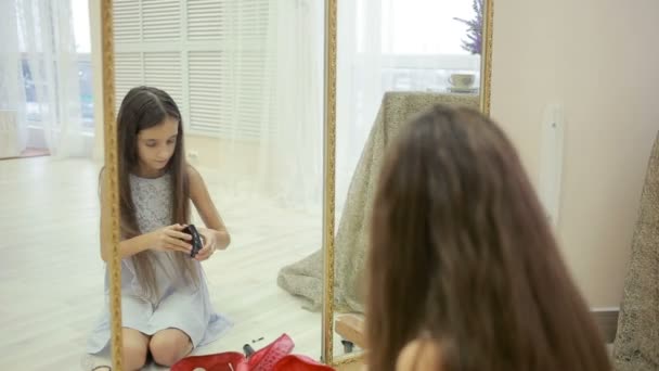 小さな女の子は彼女の母親の化粧鏡の前に描かれています。 — ストック動画