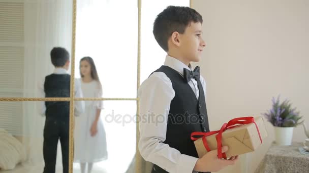 Gadstuke alegre chico en pajarita celebración de un regalo con — Vídeos de Stock