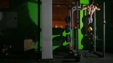 Gömleksiz adam yatay bir çubuk üzerinde Mide Egzersizleri yapıyor. CrossFit. egzersiz