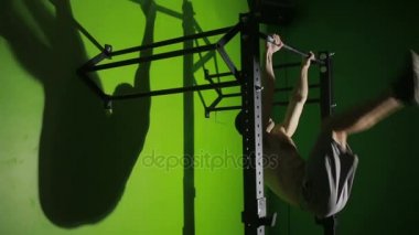 Gömleksiz adam yatay bir çubuk üzerinde Mide Egzersizleri yapıyor. CrossFit. egzersiz