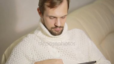 bir tablet ile kanepede ceketli genç sakallı adamı