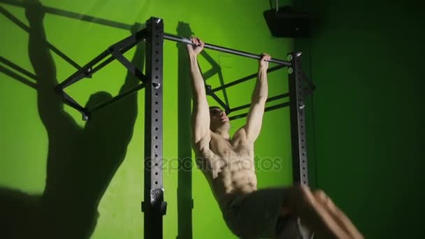 Hombre sin camisa haciendo ejercicios estomacales en una barra horizontal. CrossFit. entrenamiento físico — Vídeos de Stock