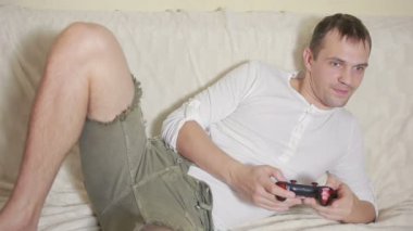 Bir karanlık odada joystick video oyunları oynarken bir kanepede oturan adam