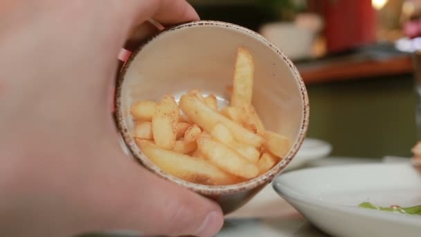 Manliga händer tar en tallrik med pommes frites i en restaurang för att äta. närbild — Stockvideo