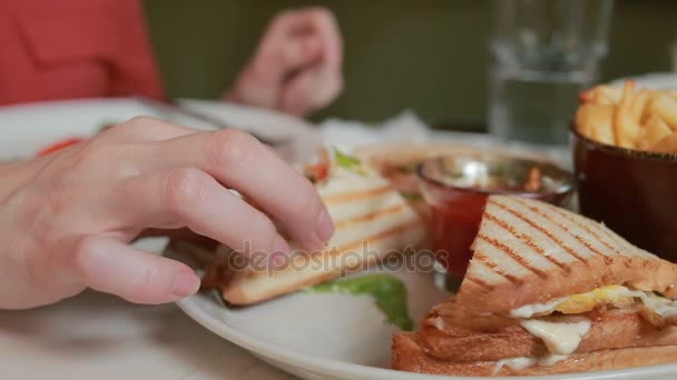 Mãos femininas que mantêm otkusanny sanduíche em um prato. Restaurante — Vídeo de Stock