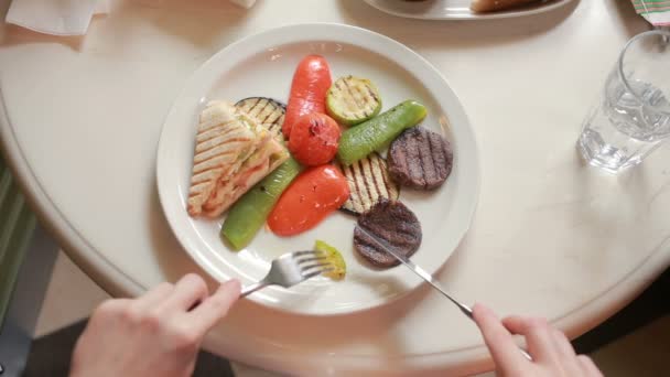 Kvinnliga händer närbild skurna grönsaker och grillat kött på en tallrik. — Stockvideo