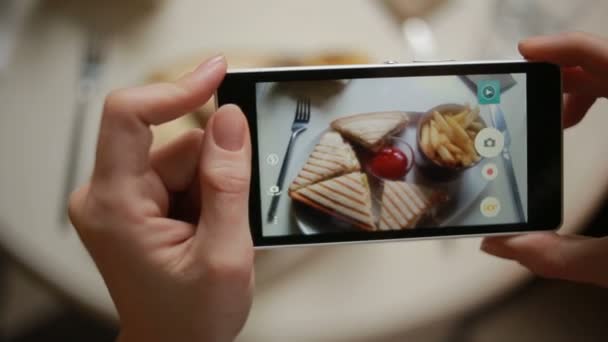 Divatos férfi egy étteremben, hogy fénykép élelmiszer mobiltelefon kamerával. szendvics