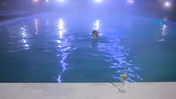 Kvinna på natten i poolen med termalvatten med ett glas champagne — Stockvideo