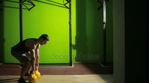 Hombre atlético joven haciendo ejercicio de swing kettlebell en el gimnasio. CrossFit — Vídeo de stock
