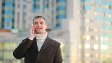bir telefonla gökdelenler arka plan üzerinde modern bir şehirde paltolu adam