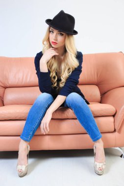 Güzel sarışın şapka bir iç çamaşırı ve kot pantolon. kanepede oturan