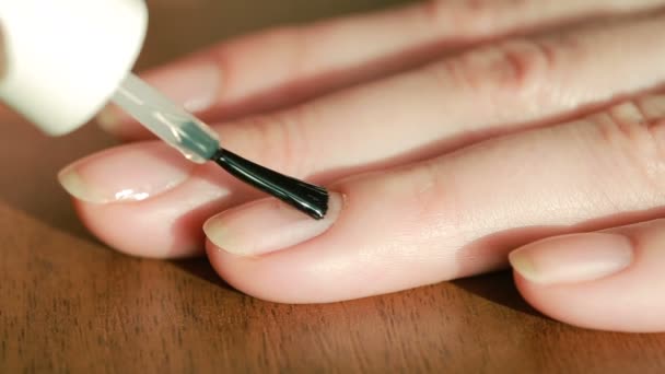 Close up of a young woman who paints her own nails with pearl lacquer on table — Stock Video