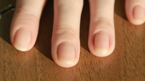 Close up of a young woman who paints her own nails with pearl lacquer on table — Stock Video