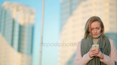 kız pembe bir ceket telefon ile modern bir şehir üzerinde yürür. gökdelenlerin arka plan