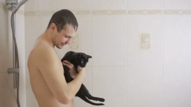 bir adam siyah bir kedi ile duş alıyor. yakın çekim