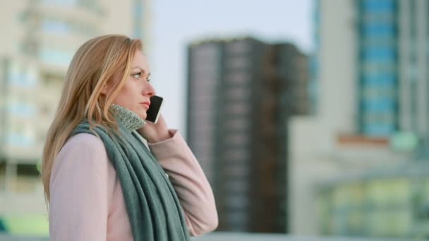 Chica en un abrigo rosa con paseos telefónicos en una ciudad moderna. fondo de rascacielos — Vídeo de stock