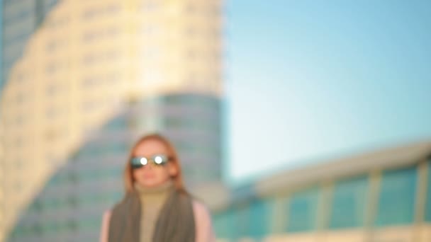 Chica en un abrigo rosa camina sobre una ciudad moderna en el fondo de los rascacielos — Vídeos de Stock