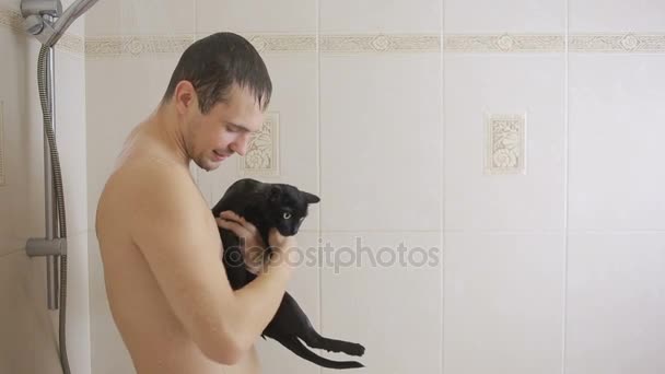 Un hombre duchándose con un gato negro. primer plano — Vídeo de stock