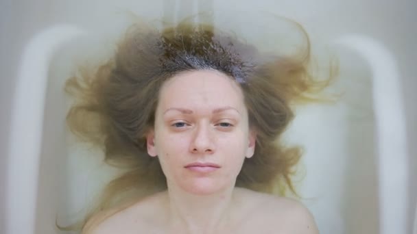 Gros plan d'une femme sans maquillage, allongée dans le bain . — Video